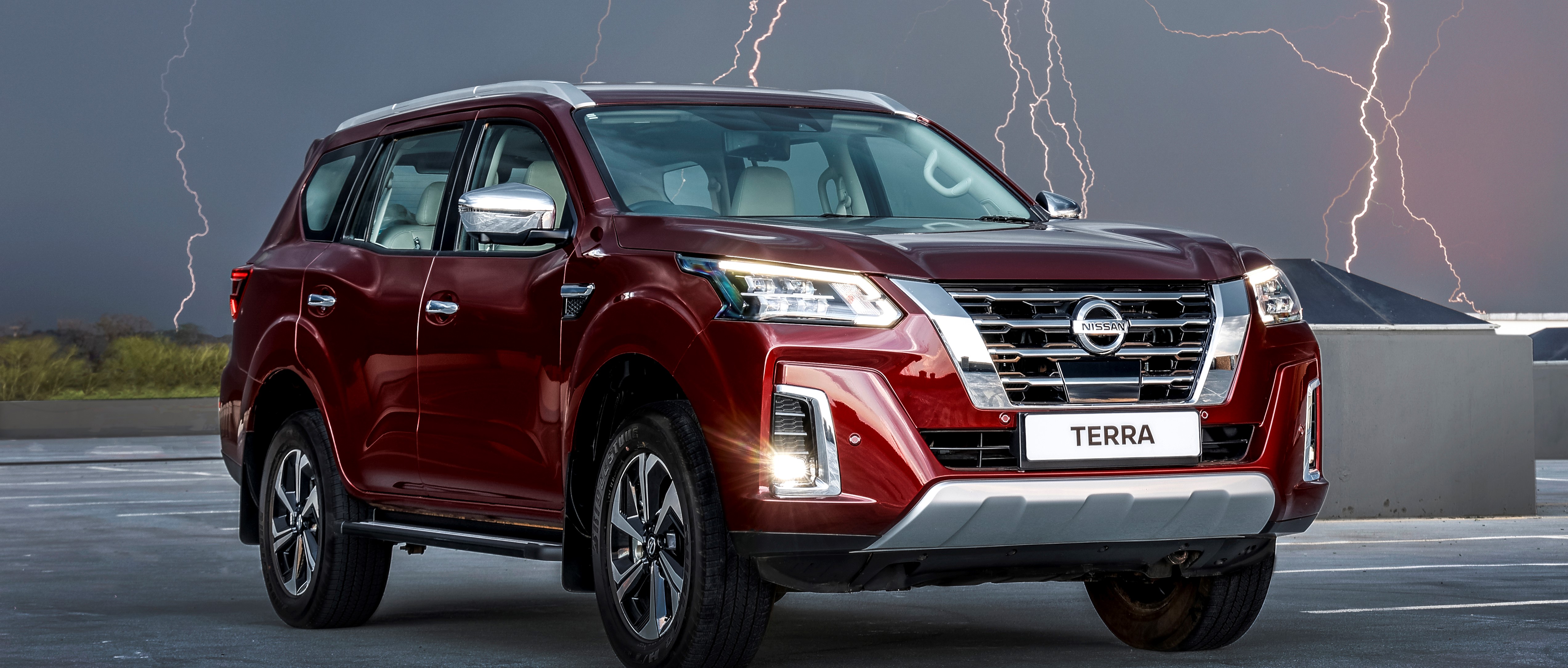 Red Nissan Terra in parking lot with lightning in the background